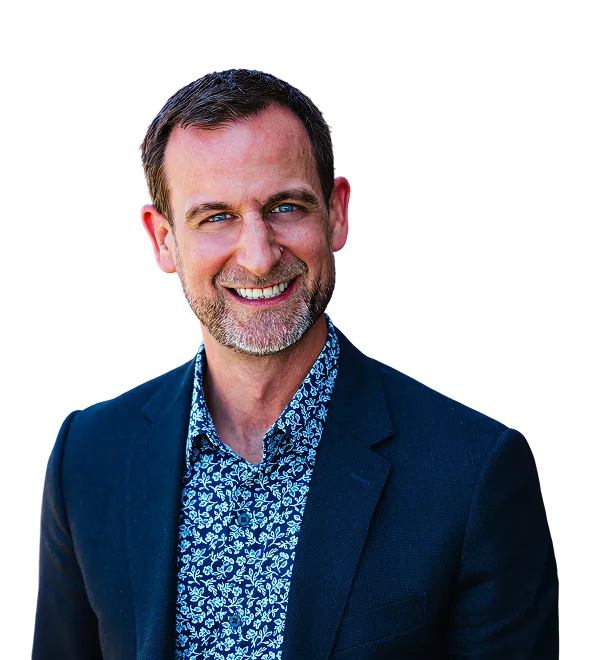 Smiling man with short hair and beard wearing a dark blazer and a blue floral patterned shirt.