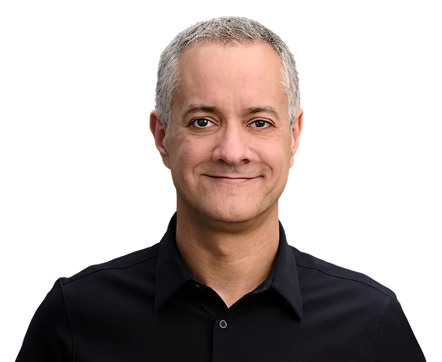 Smiling middle-aged man with short gray hair wearing a black collared shirt against a plain background.