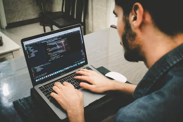 An employee coding AI and machine learning scripts on a laptop.
