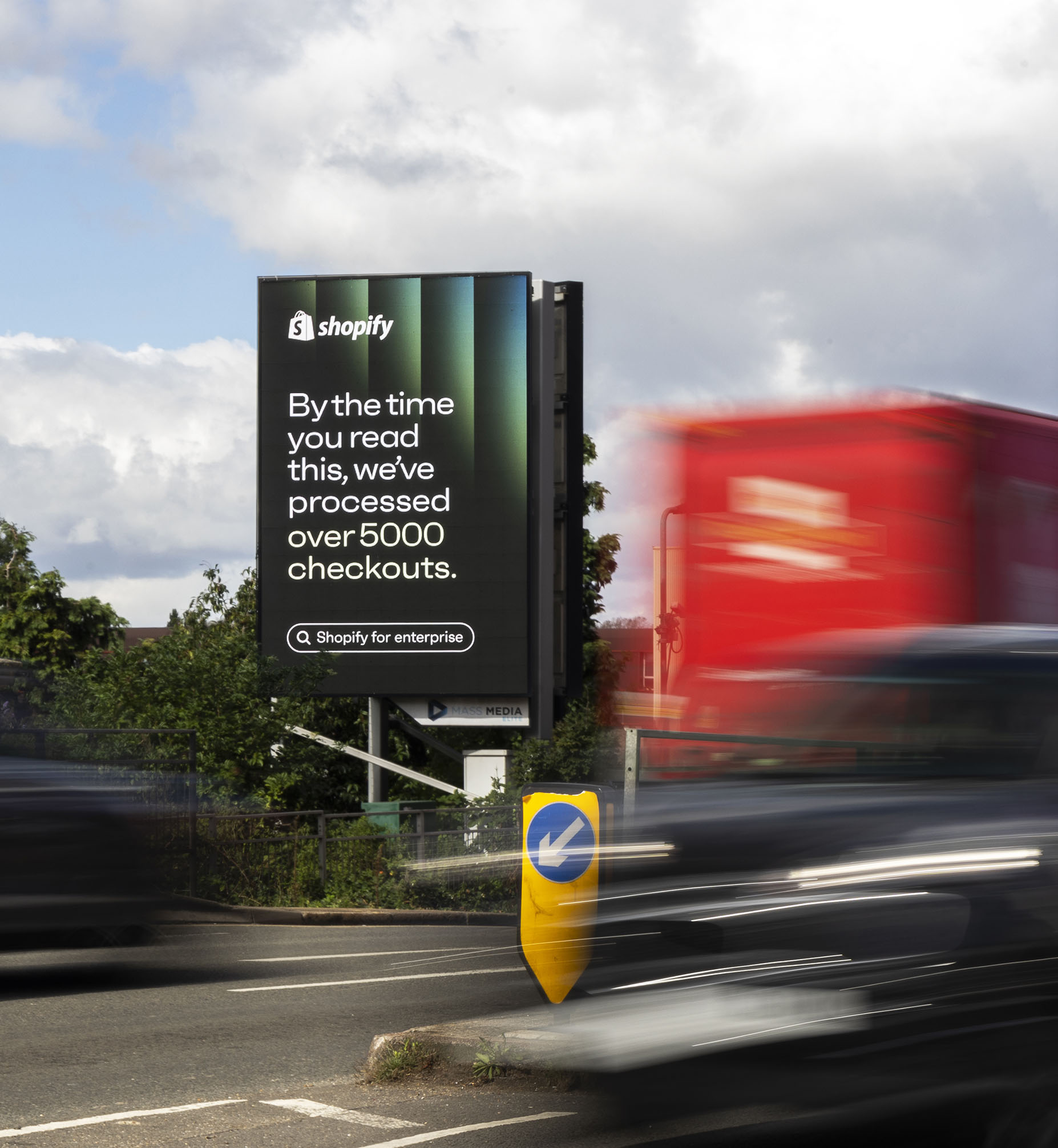 Roadside digital billboard showing a Shopify ad that says, 'By the time you read this, we've processed over 5000 checkouts.'
