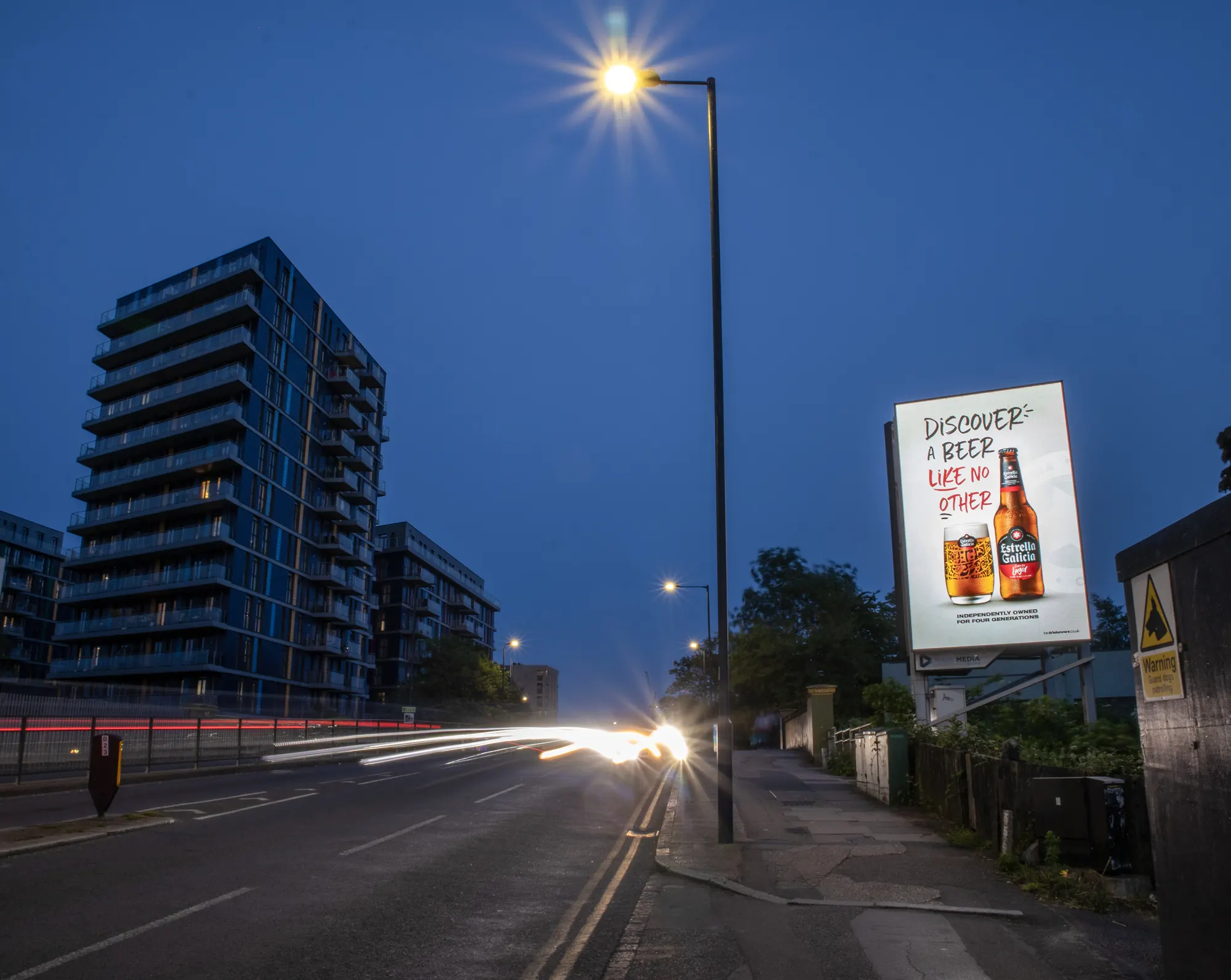 Premium roadside digital billboard at dusk with a modern residential tower behind it, reflecting DOOHable's founding philosophy