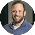 Headshot of a smiling man with a beard, wearing a blue polo shirt.