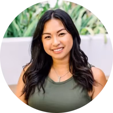 Portrait of a smiling woman with long dark hair, wearing an olive green tank top.