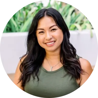 Portrait of a smiling woman with long dark hair, wearing an olive green tank top.