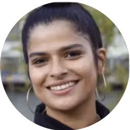 Headshot of a smiling woman with her hair in a bun and large hoop earrings.