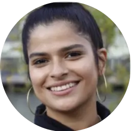 Headshot of a smiling woman with her hair in a bun and large hoop earrings.