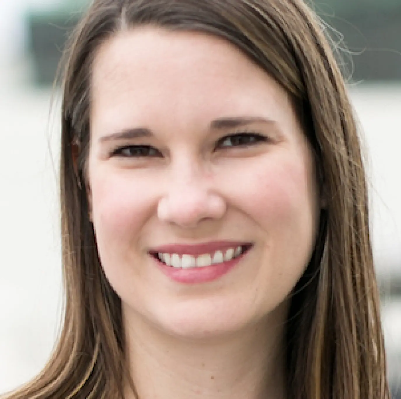 Close-up headshot of a smiling woman with straight brown hair.