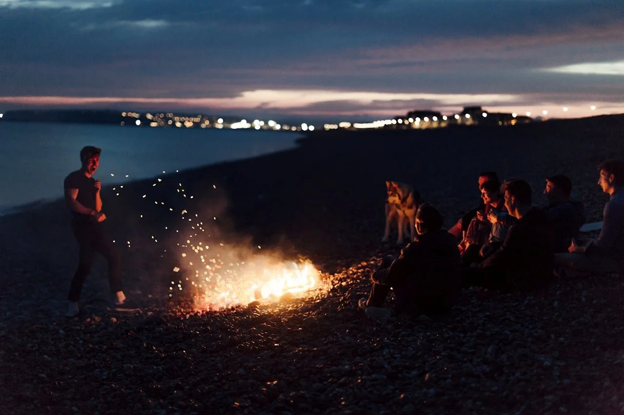  These are real people laughing at a silly goose by a bonfire. 