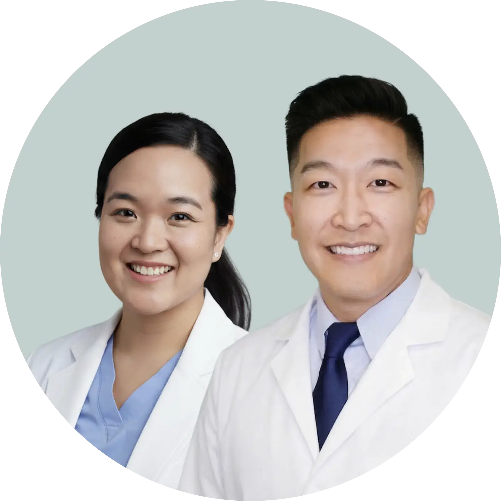 Smiling male and female doctors wearing white coats on a light gray background.