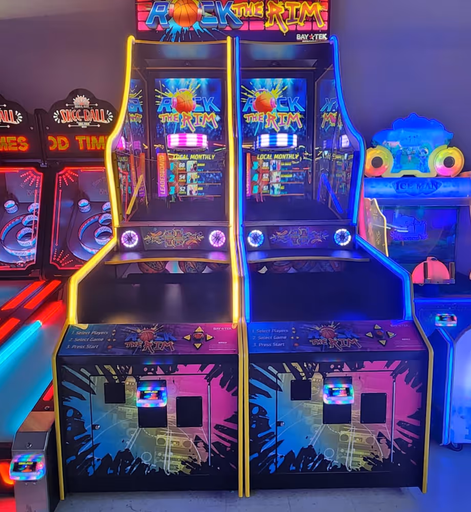Two neon-lit Rock the Rim basketball arcade game machines side by side with vibrant colors and digital score screens.