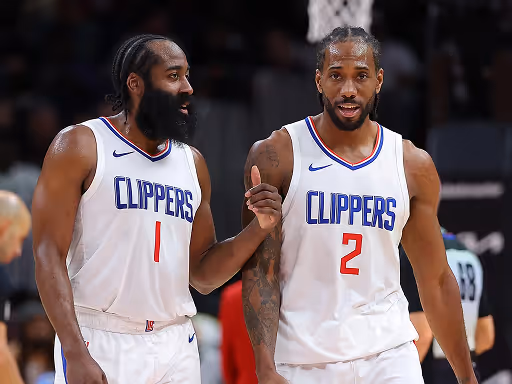 Two basketball players from the Los Angeles Clippers in white uniforms, with numbers 1 and 2, engaged in discussion on the court.