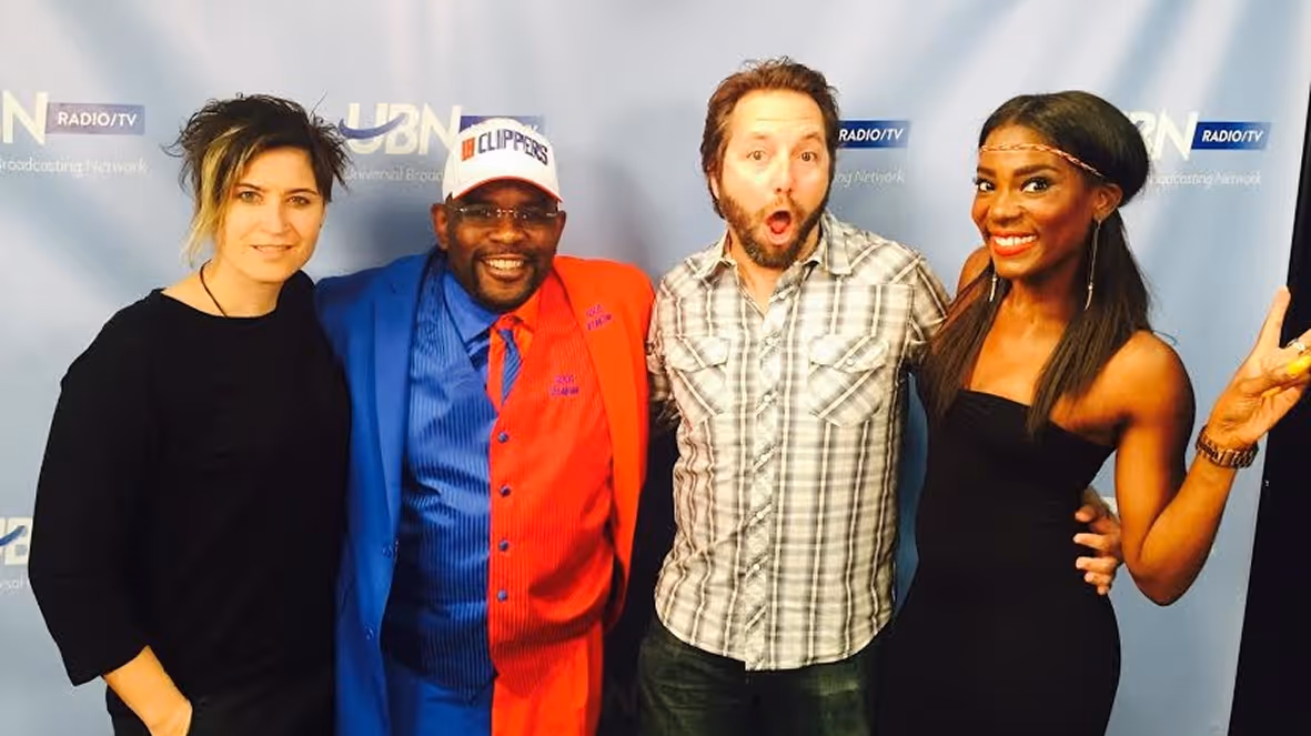 Four people posing in front of a UBN Radio/TV backdrop, smiling and making playful expressions.