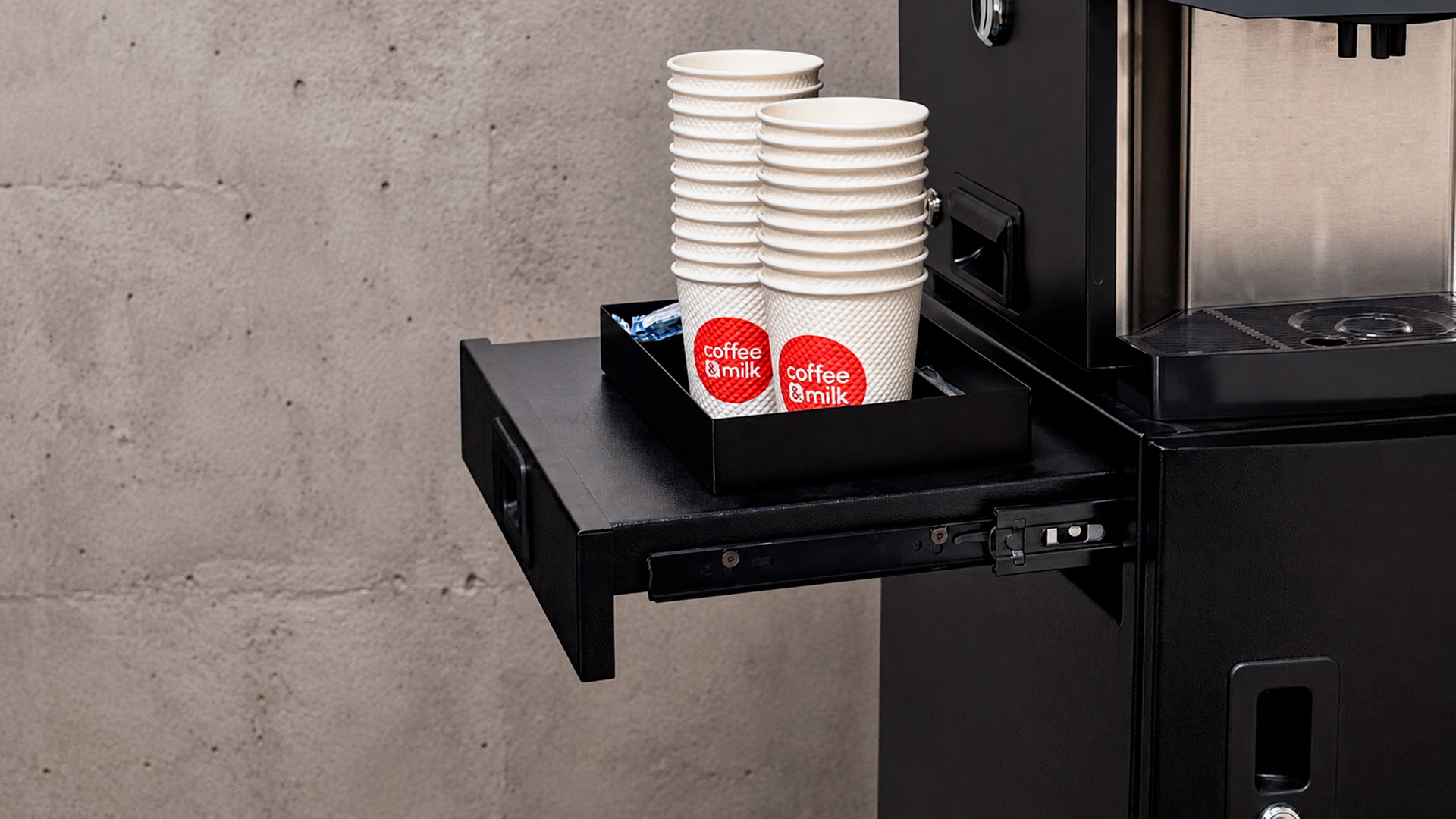 Mueble Torino de Coffee & Milk con la bandeja abierta, vasos con la marca y la máquina de café encima