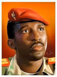 Portrait of a man wearing a military uniform and a red beret with a star emblem, set against an orange background.
