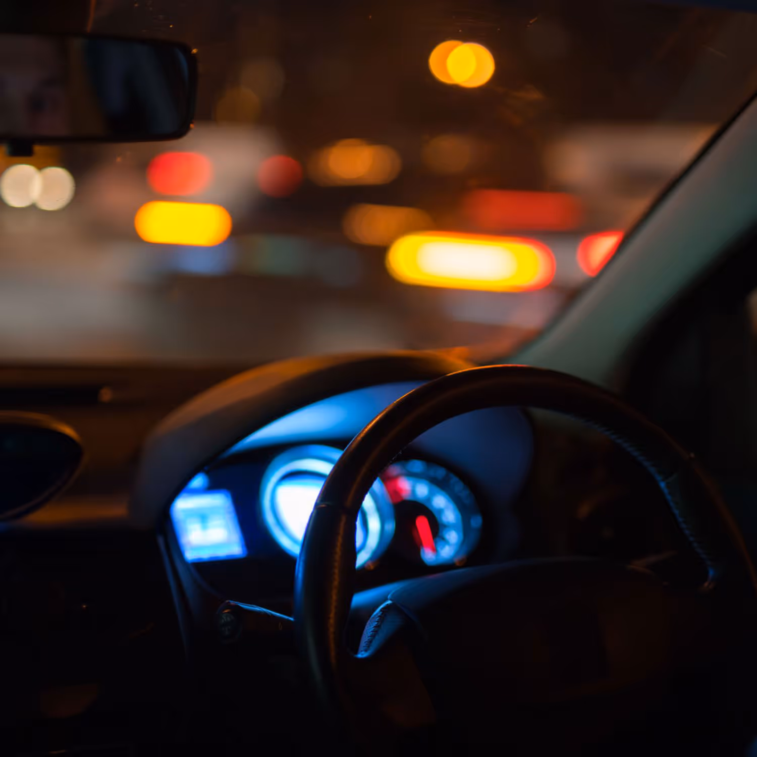 Two people seated across from each other at a glass-top metal table with two glasses of water, a notebook, a pen, and glasses on the table.