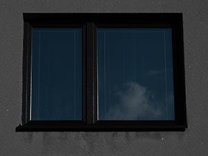 Double-pane window with dark frame reflecting a cloudy sky.