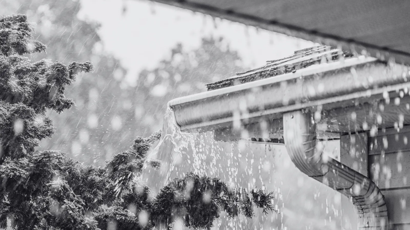 Rainwater overflowing from a clogged rain gutter during a heavy thunderstorm.