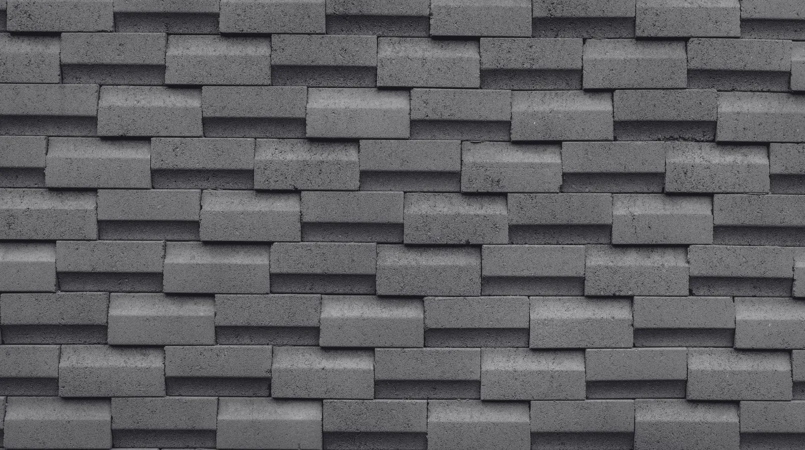 Gray interlocking concrete blocks stacked in a staggered pattern forming a textured wall.
