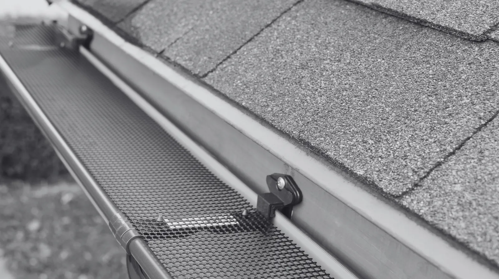 Close-up of a roof gutter fitted with a mesh guard to prevent debris from entering the gutter system.