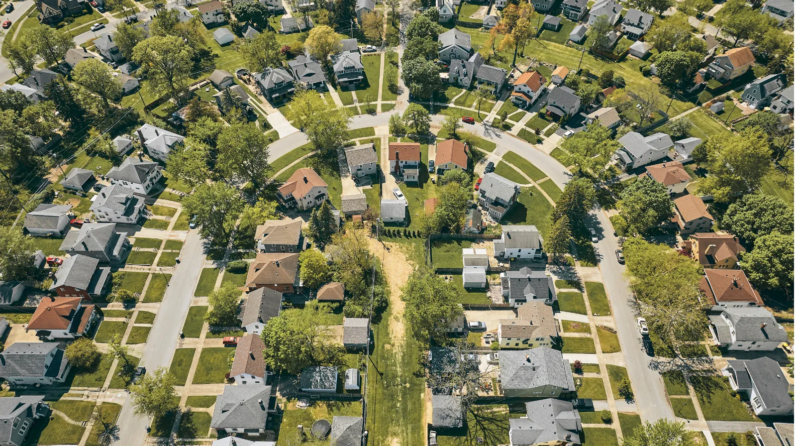 Aerial view of a suburban neighborhood in Midwest Ohio featuring houses with varied roof colors and green lawns along a curving street.