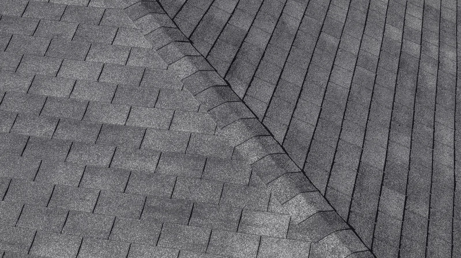 Close-up of gray asphalt roof shingles showing overlapping rows and ridge detail.