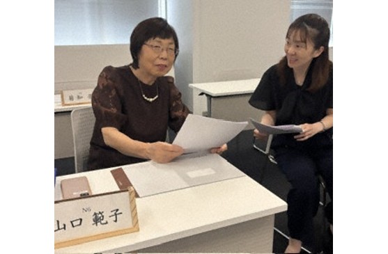 農業委員会総会前に新田涼子委員と情報交換する山口さん(左)