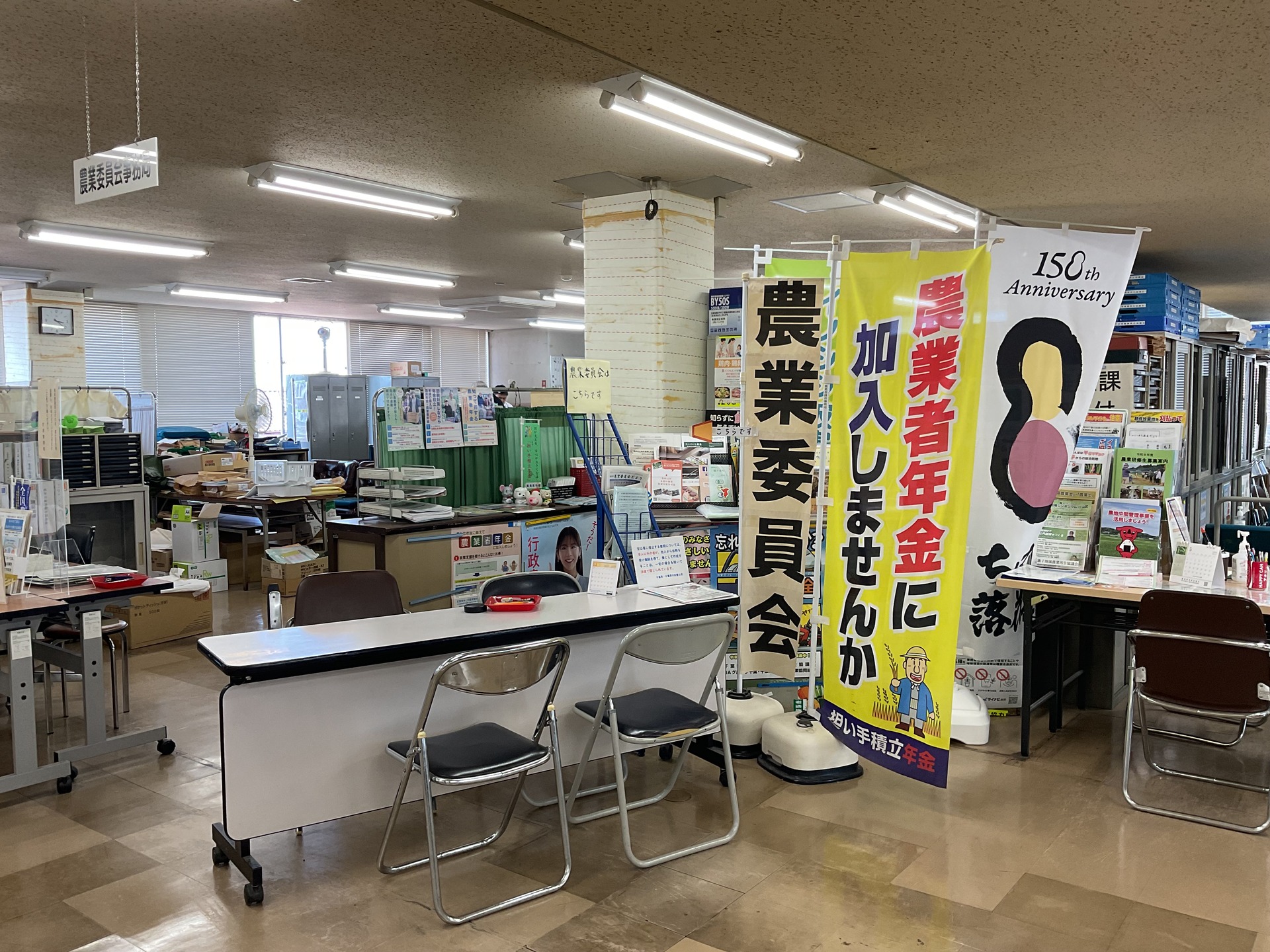 窓口では農業者年金ののぼりを立てPR、 (左) 窓口の机の上には訪問者に節税を伝えるメッセージボードを設置