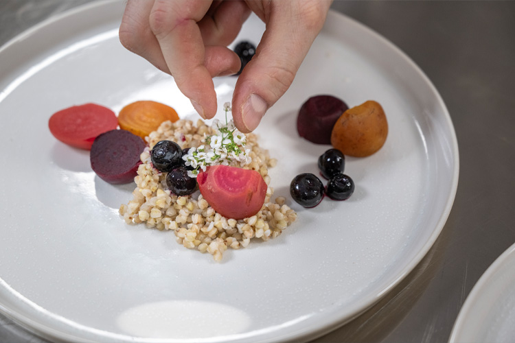 Anrichten eines Gerichts mit Roter Bete, Buchweizen und Heidelbeeren