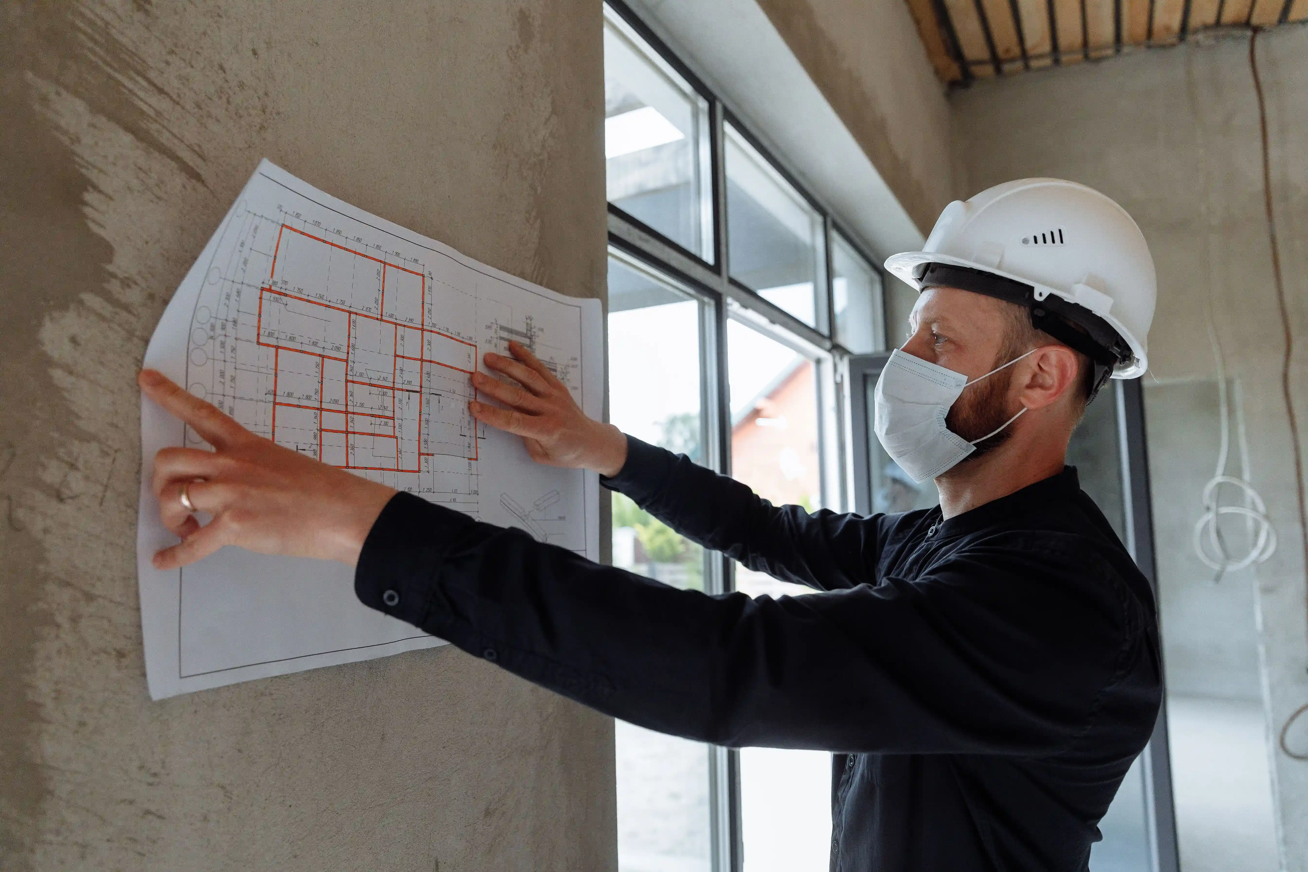  A construction inspector analyzing floor plans on-site, illustrating manual property inspection methods that can be optimized using h3zoom.ai technology. 