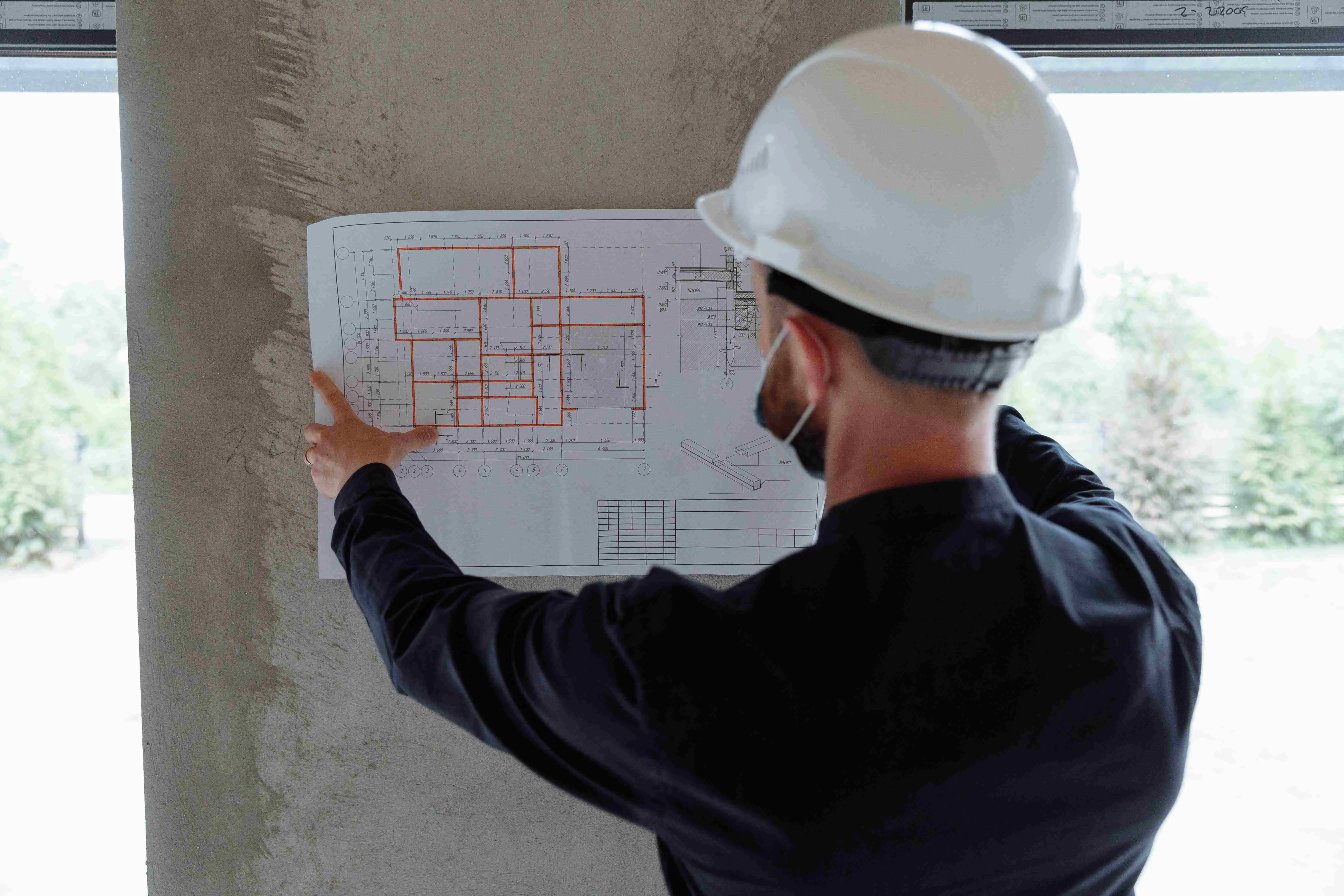A property inspector evaluating floor plans during a building survey, representing data verification and facade inspection planning for h3zoom.ai. 