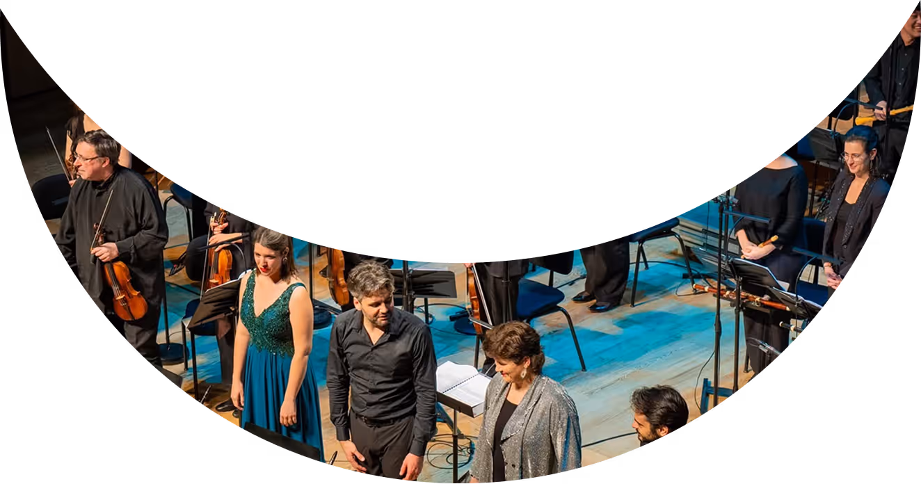 Orchestra on stage with musicians and vocalists in formal attire after a performance.