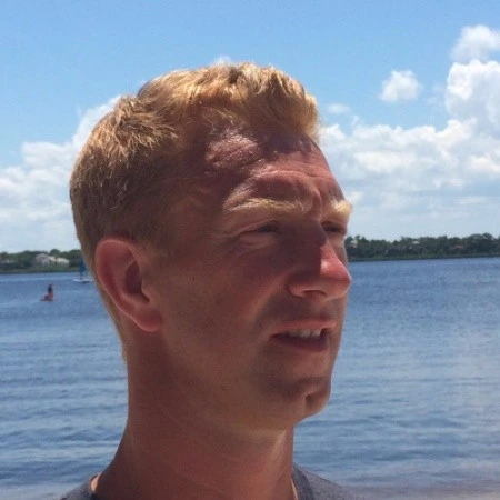 David Decoene légèrement de profil, les cheveux blonds et une étendue d'eau en arrière plan