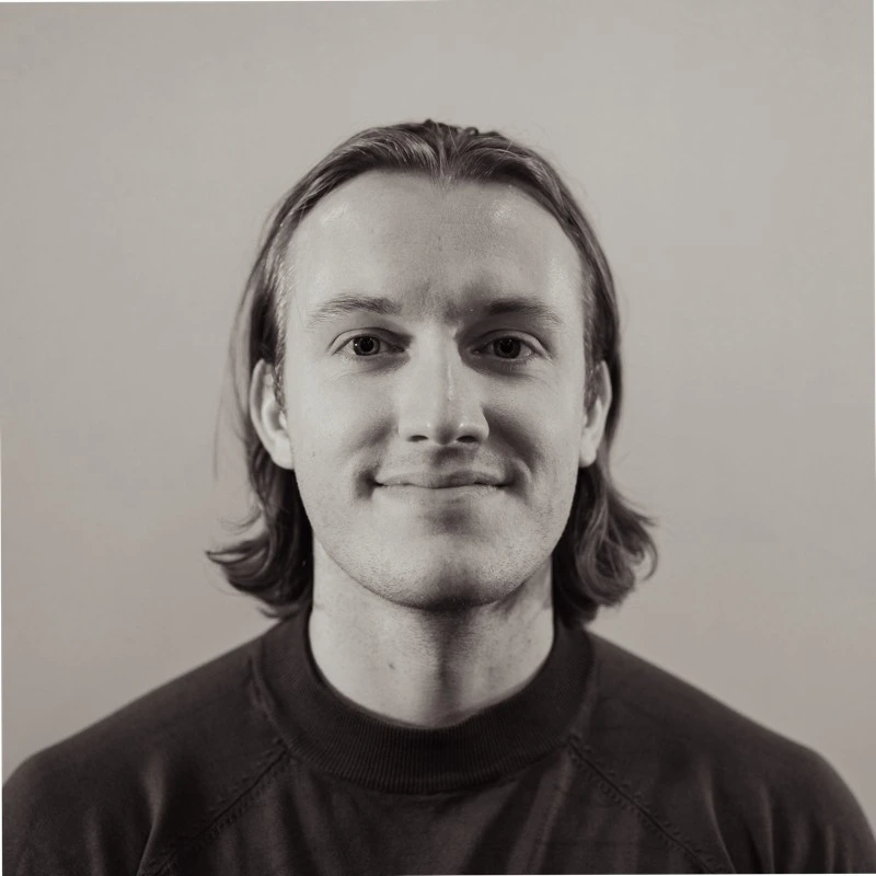 Théo Chaumay dans des teintes grises, de face, avec des cheveux longs jusqu'au cou et placés derrière ses oreilles