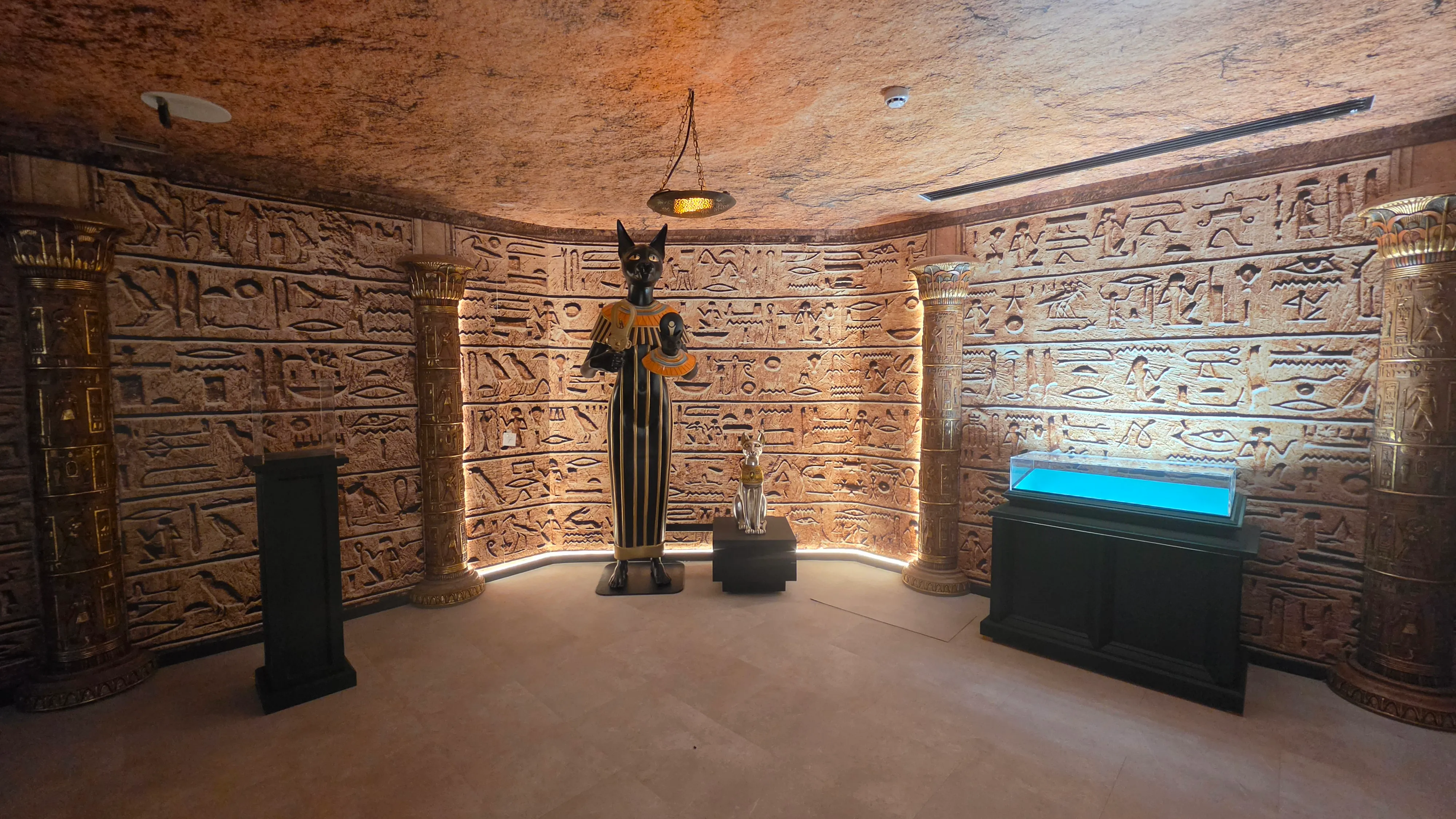 Salle égyptienne de l'escape game Le tombeau de Bastet, statue de Bastet entre des colonnes et des murs de hiéroglyphes