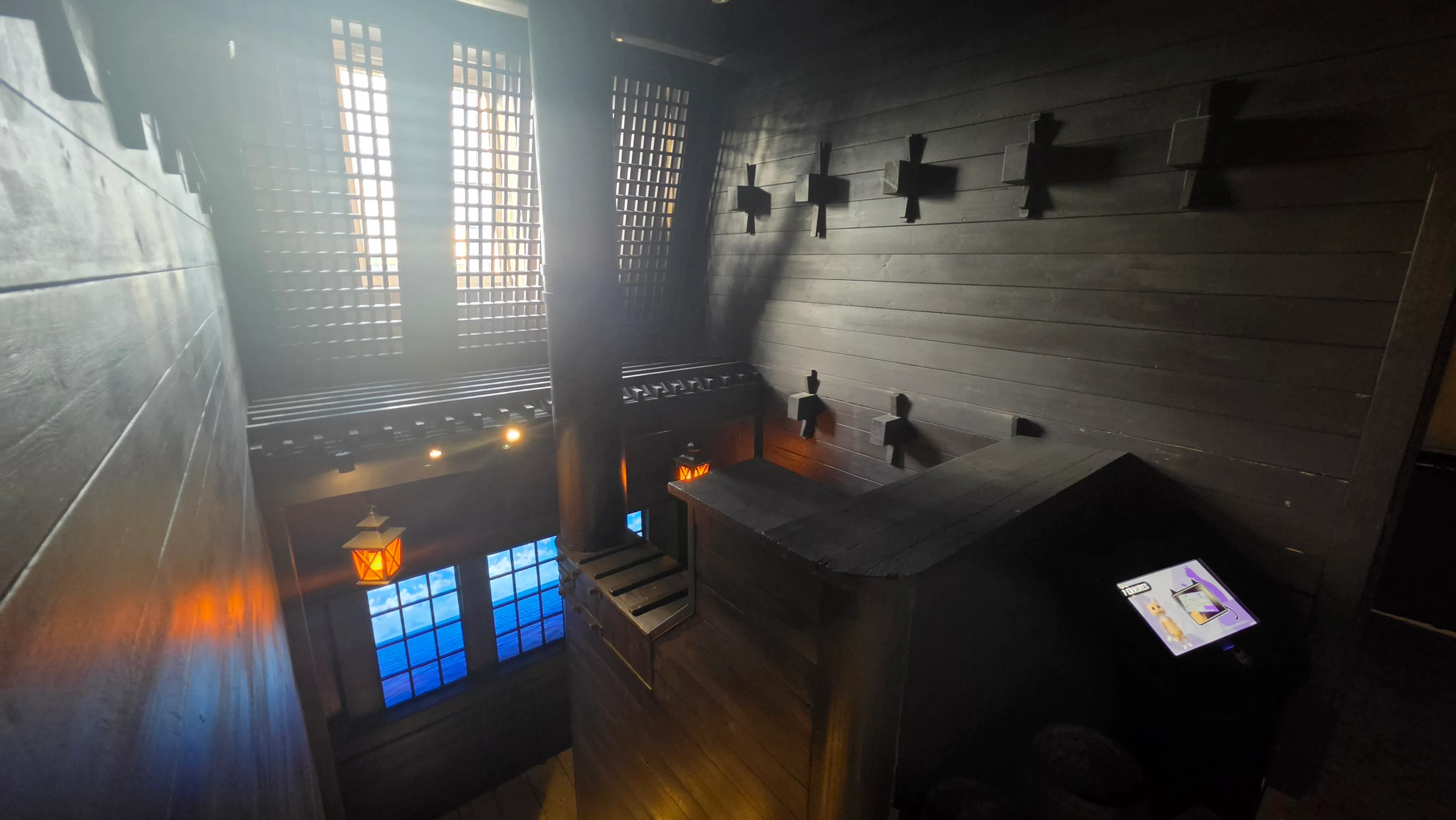 Décor médiéval en bois sombre de l'escape game La malédiction du chat noir, vitraux bleus et lanterne