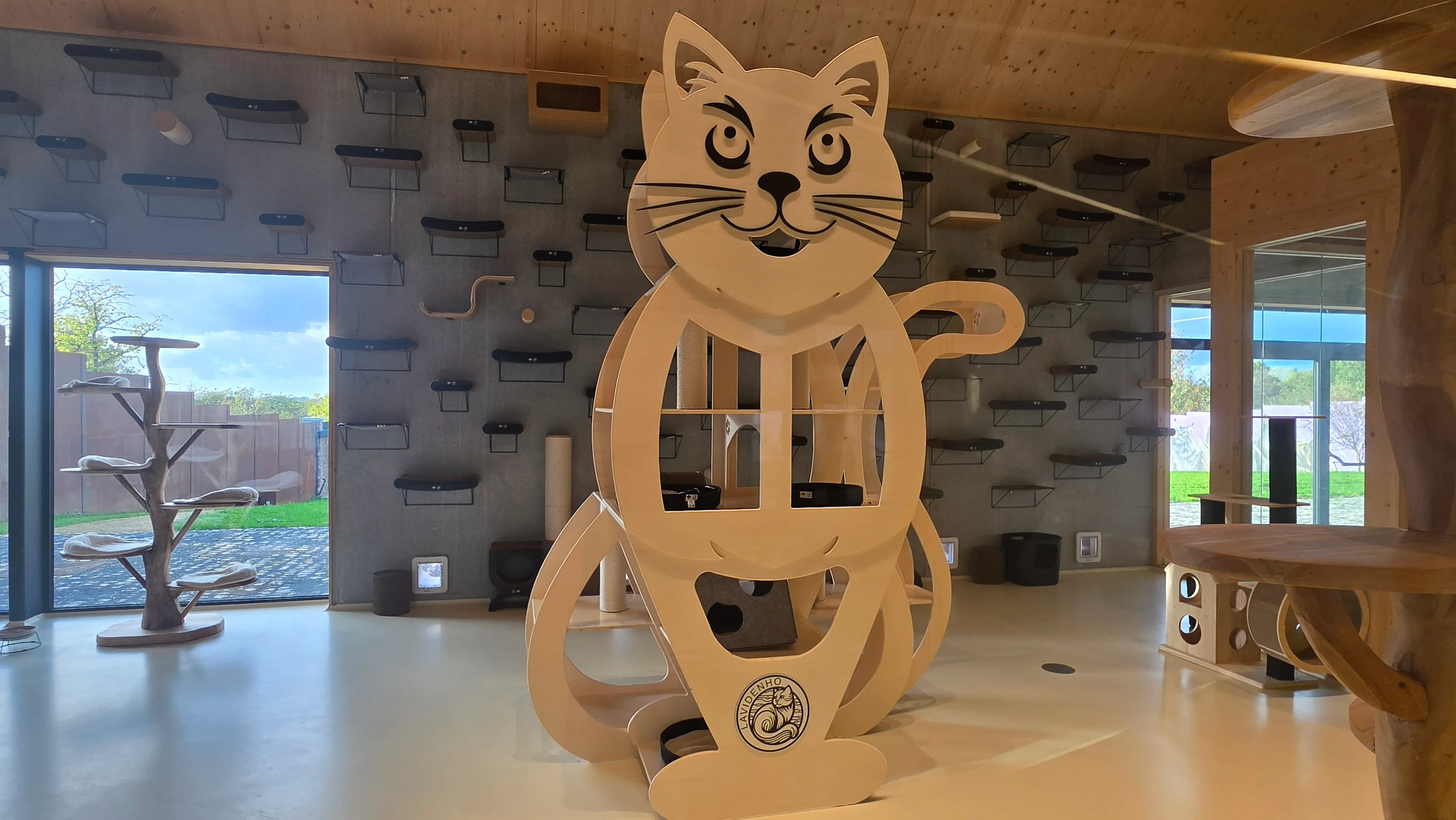 Espace de vie intérieur des chats avec une grande structure en bois en forme de chat et des étagères murales d'escalade