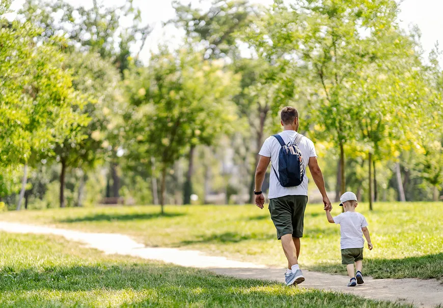 Blue ferry boat cruising on calm water with city buildings and a setting sun in the background.