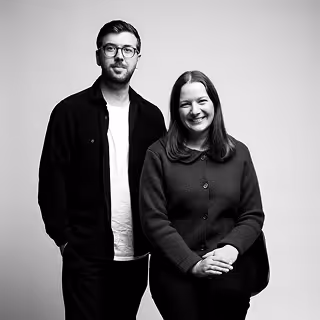 Un homme et une femme posant ensemble, en noir et blanc, avec un fond uni.