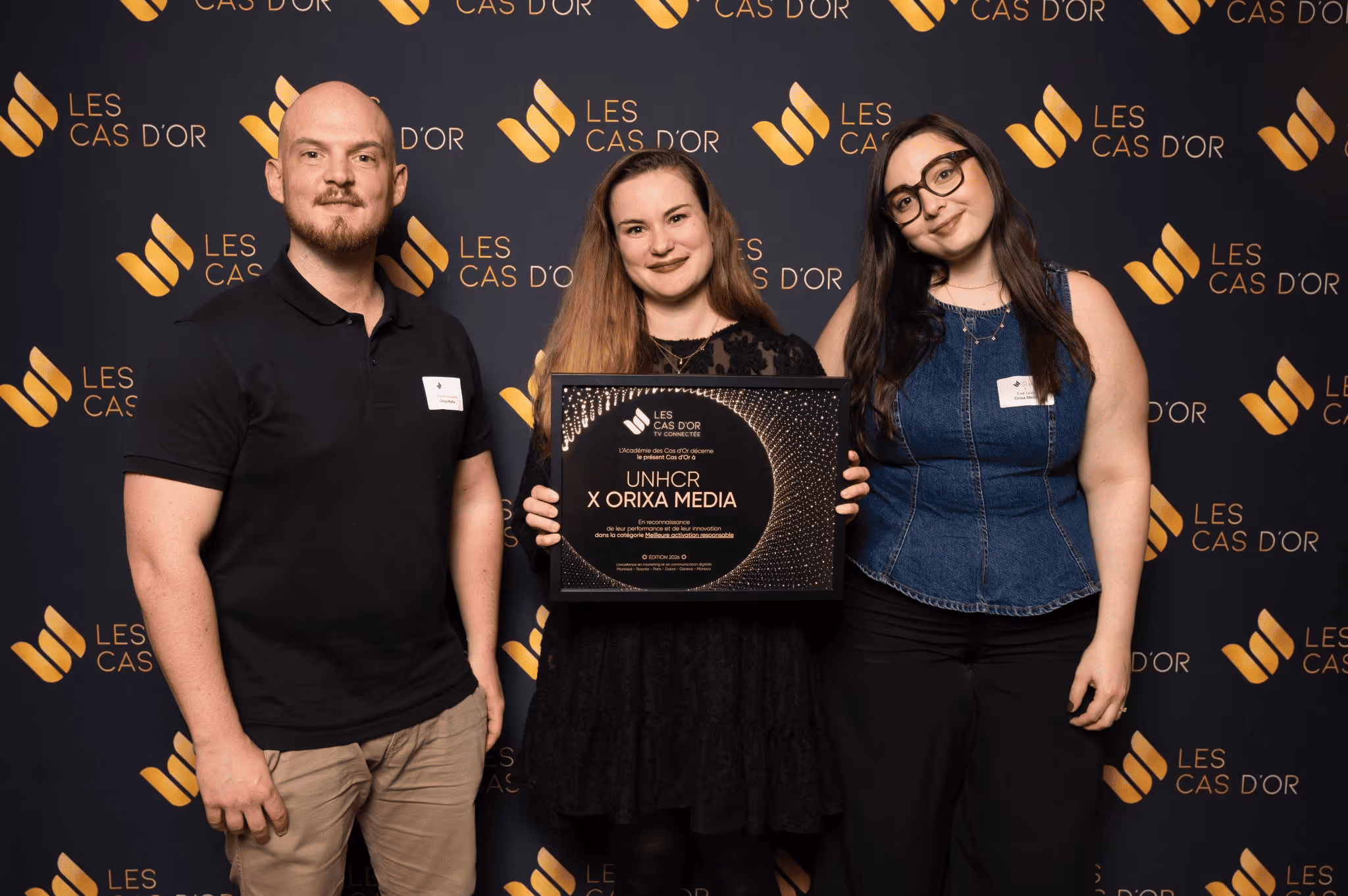Trois personnes souriantes tiennent un prix remporté au Cas d'Or