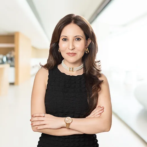 Confident woman in a black dress, standing with arms crossed in a modern setting.