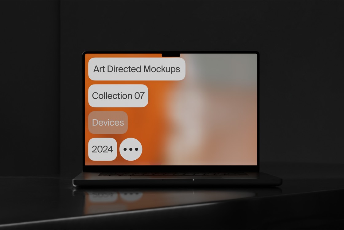 Laptop on dark surface displaying a blurred orange and gray background with text labels: Art Directed Mockups, Collection 07, Devices, 2024.