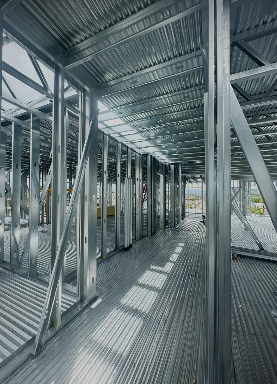 Interior view of a building under construction showing steel framing and corrugated metal decking.