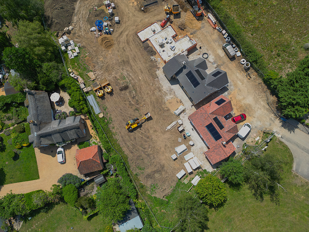 Vue aérienne d'un chantier avec deux maisons en construction équipée de panneaux solaires.