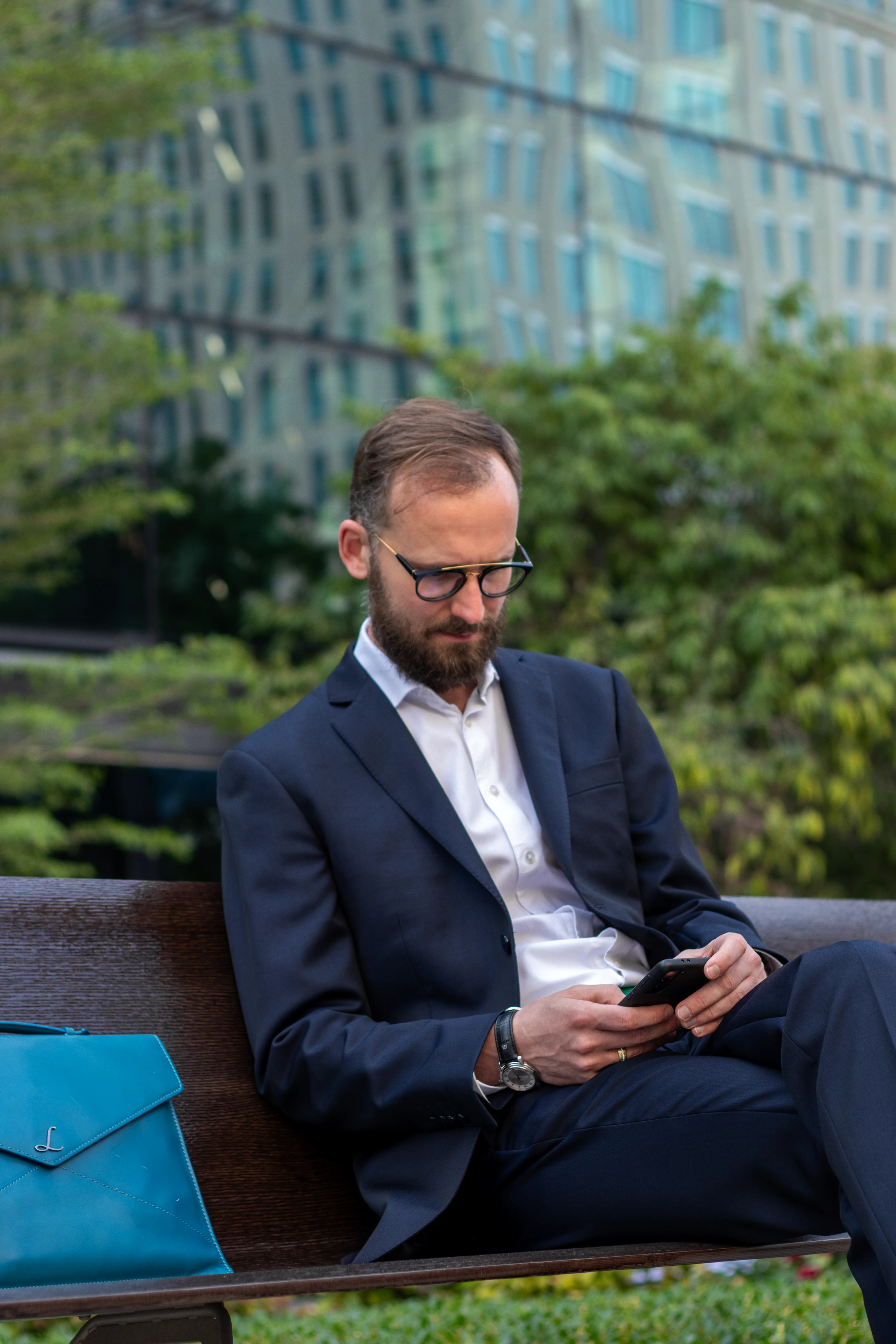 Checking a phone on a bench outside a glass office tower