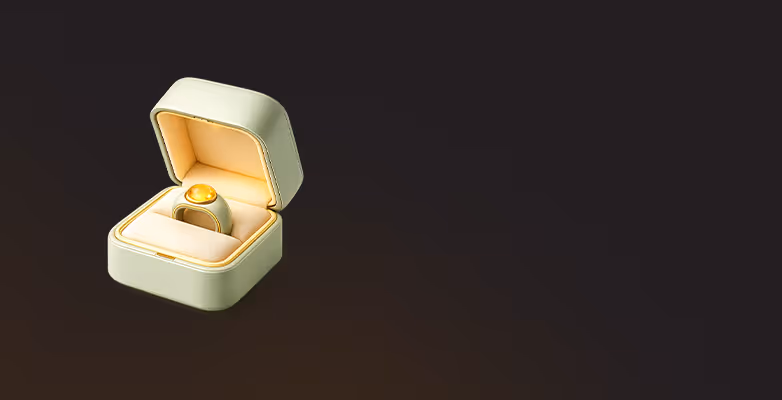 Gold ring with a large round yellow gemstone inside an open cream-colored jewelry box.