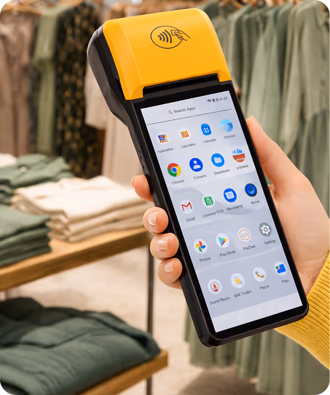Hand holding a yellow and black point-of-sale device with a touchscreen displaying various app icons in a clothing store.