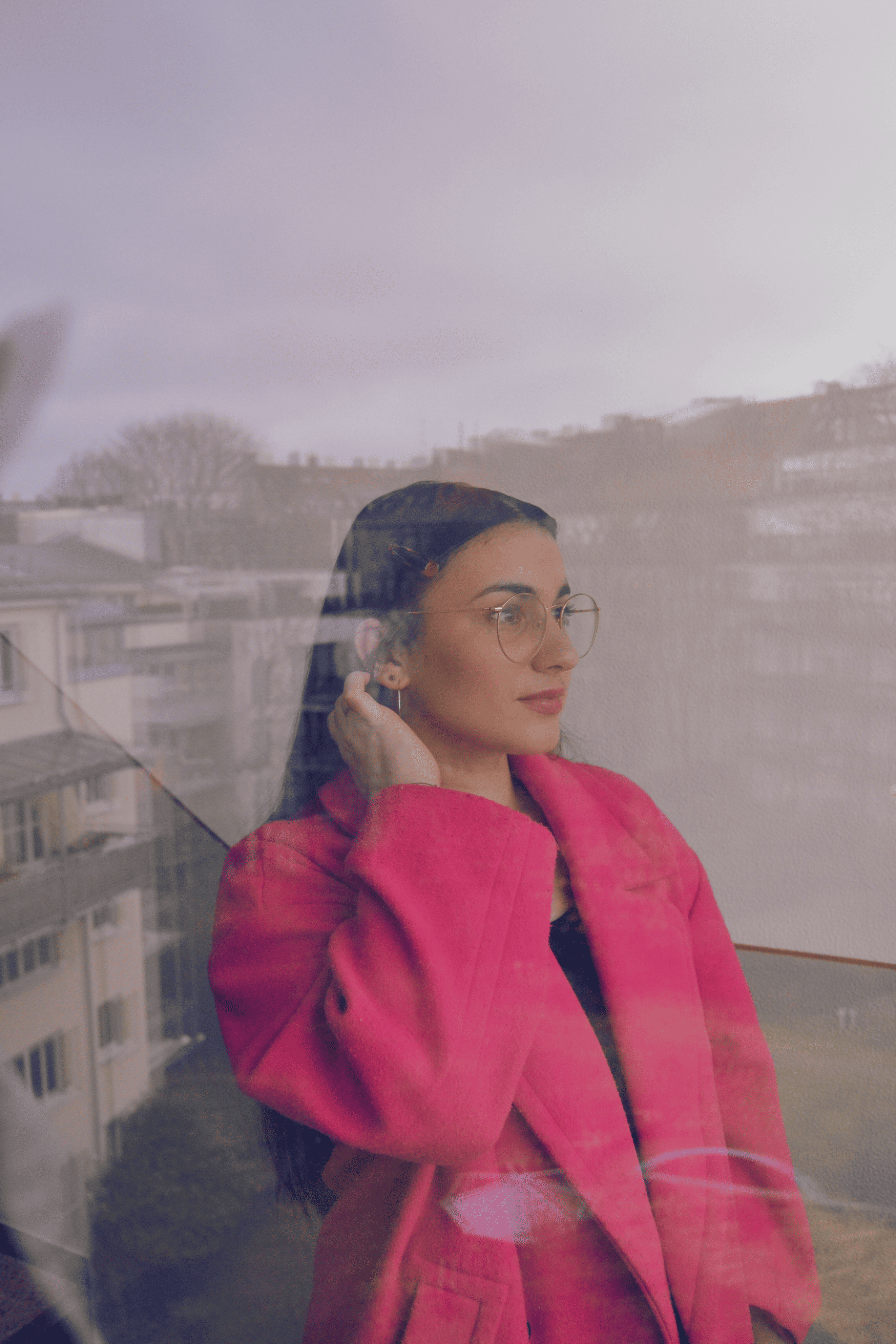 Image of Marie-Claire in a pink coat looking at the distance