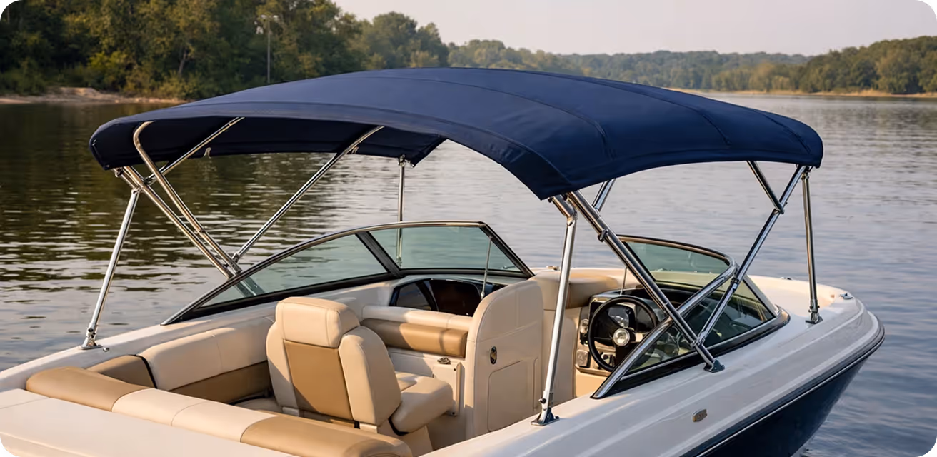 White motorboat with tan seats and a blue fabric canopy floating on a calm lake with forested shoreline in the background.