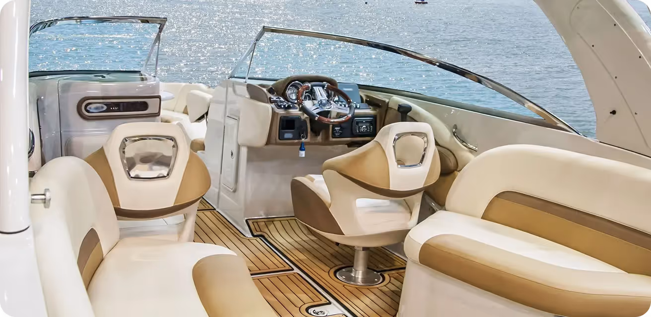 Interior view of a luxury motorboat showing beige and brown leather seats, a steering wheel, and a clear windshield with water visible in the background.