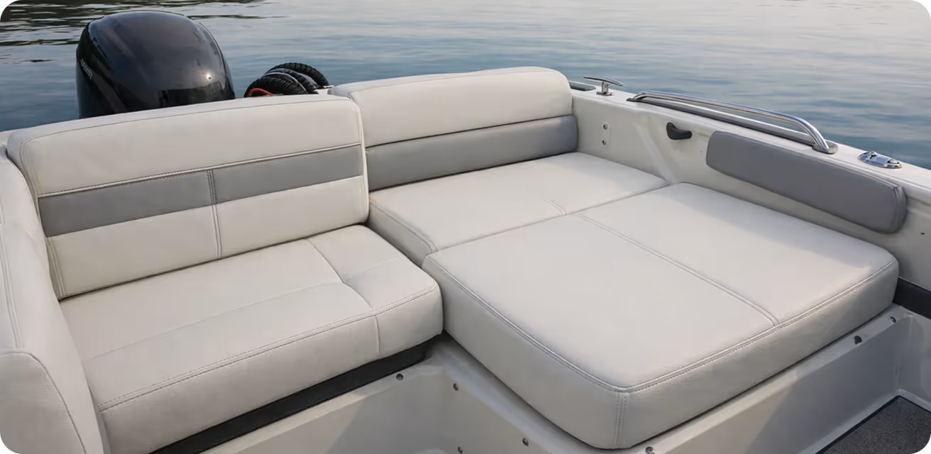 White cushioned seating area on a boat with calm water in the background.